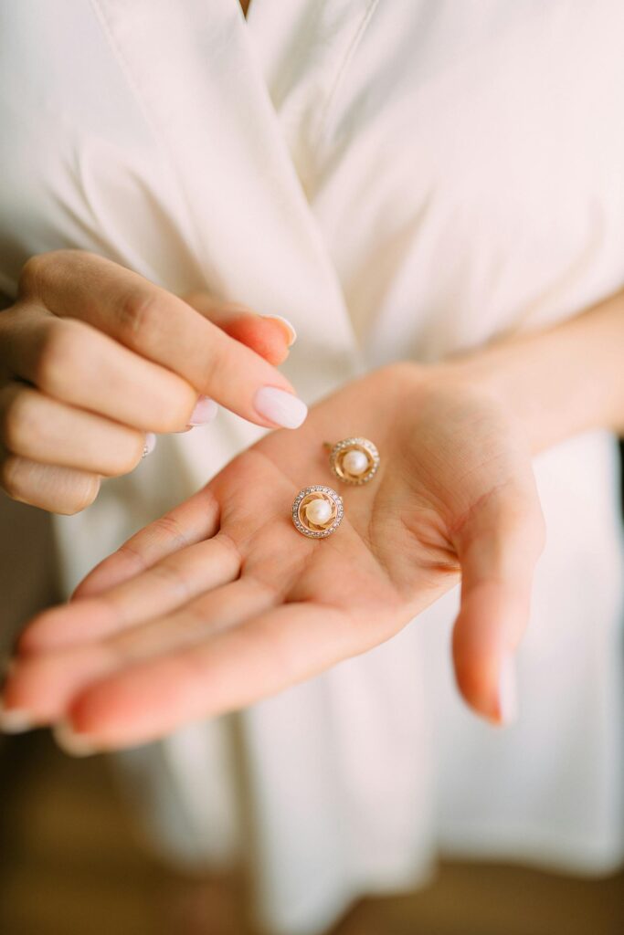 Close-up of elegant pearl earrings held in a hand, showcasing luxury jewelry.