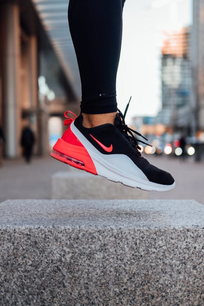 A person in mid-air with stylish sneakers and black leggings in an urban environment, capturing movement and style.